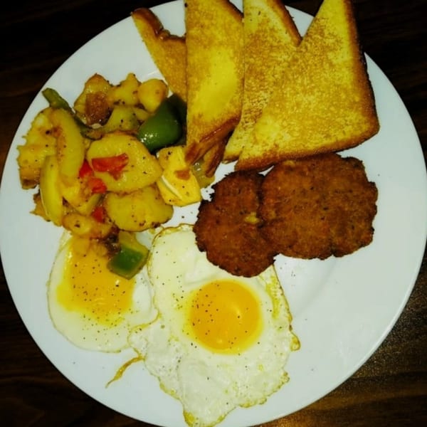A Gutbusters Breakfast plate with fried eggs, home fries, hash browns, and toast.