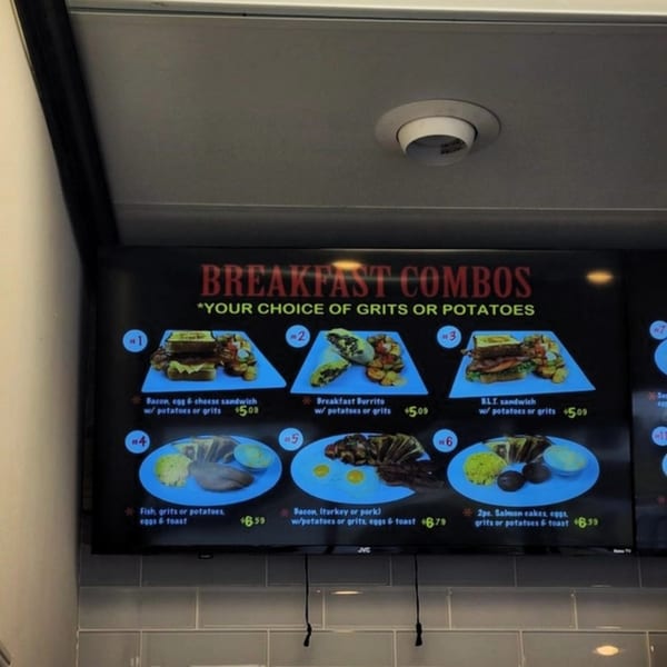 A digital menu board displays various breakfast combo meals with images and prices at Gutbusters Breakfast.
