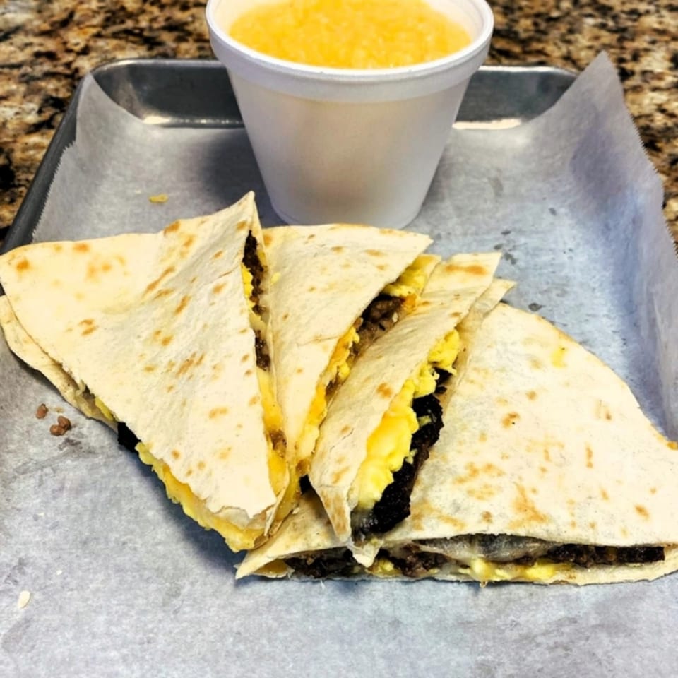 Breakfast quesadillas with scrambled eggs and sausage, served with a side of grits.